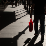 Person walking in a crowd carrying a red bag